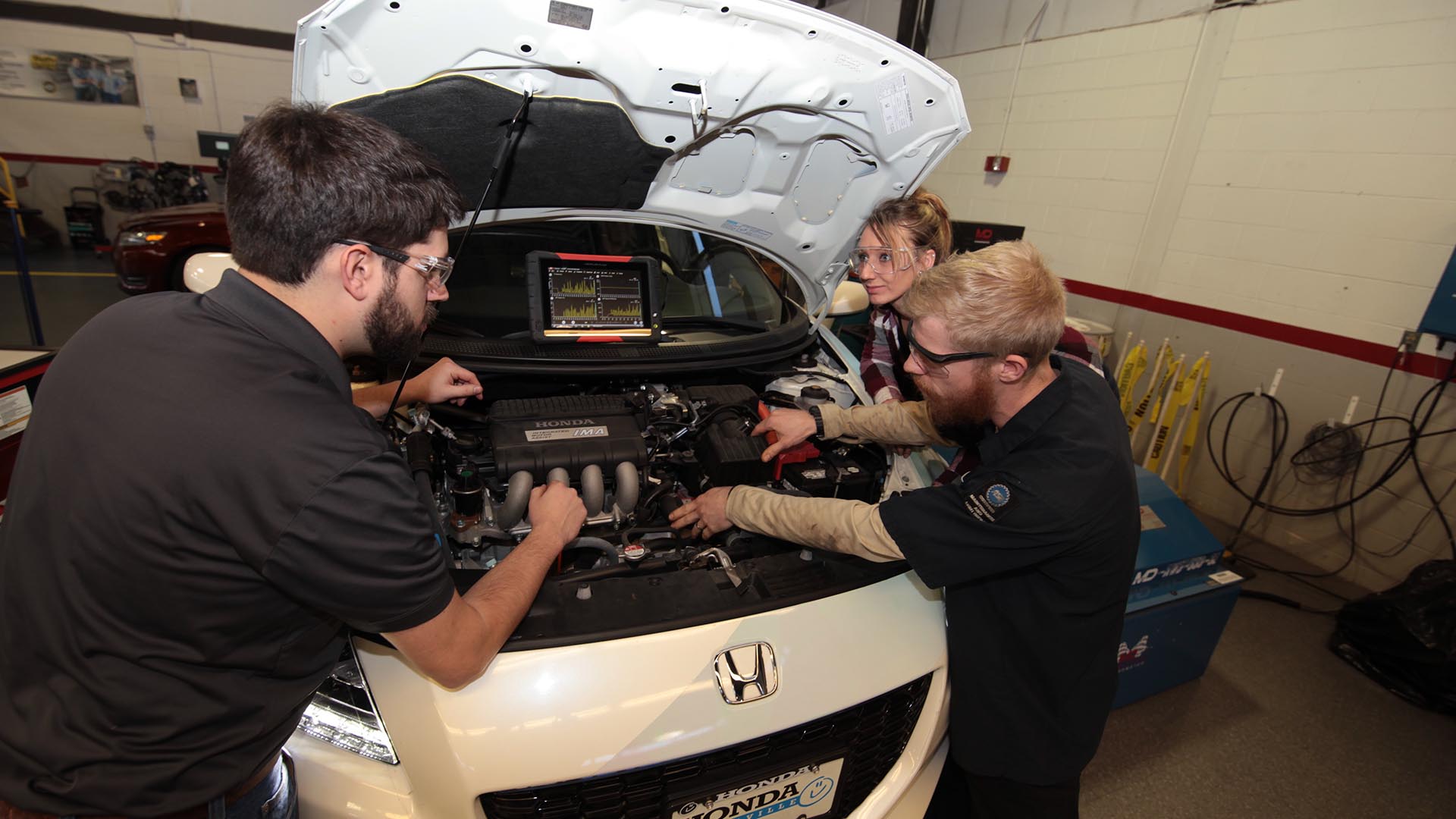 Group of students working on car engine